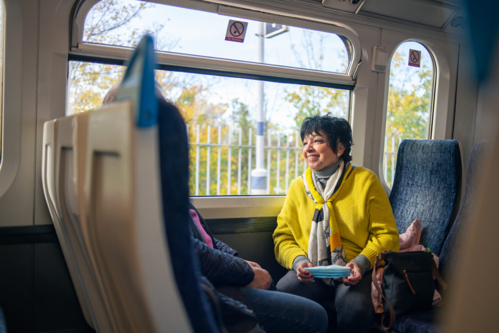 Smiling woman wearing yellow coat and sitting on a train