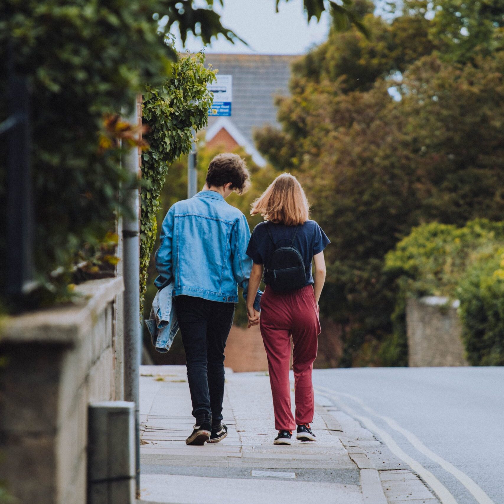 Two people walking on pavement and holding hands